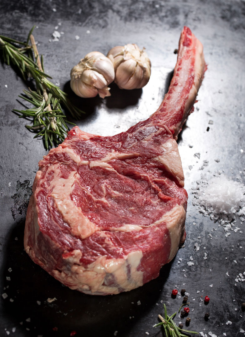 Tomahawk steak on dark surface